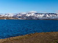 Heiðarvatn und schneebedeckte Gebirgskette auf Fahrt in den Seyðisfjörður - Ostfjorde